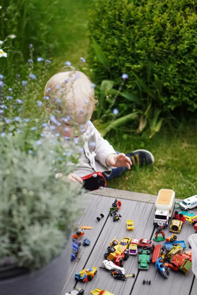Kleinkind Garten Spielzeug Spielzeugautos spielen Terrasse